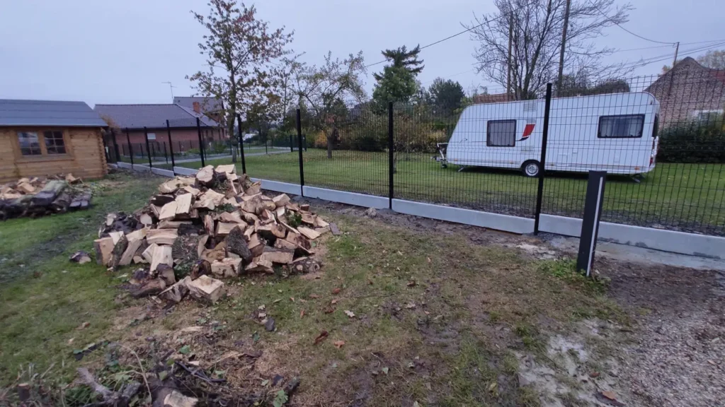 Tas de briques et débris de construction sur un chantier avec caravane et clôture métallique