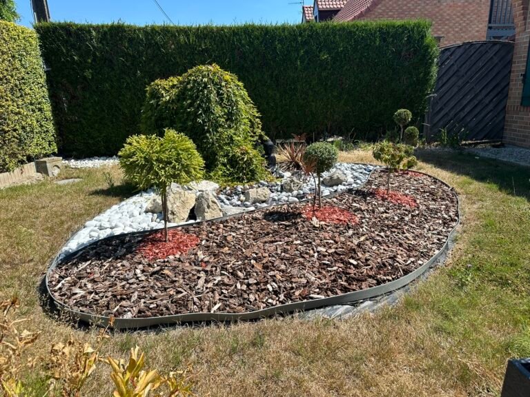 Parterre paysagé avec paillis, arbustes taillés et bordure noire dans un jardin résidentiel